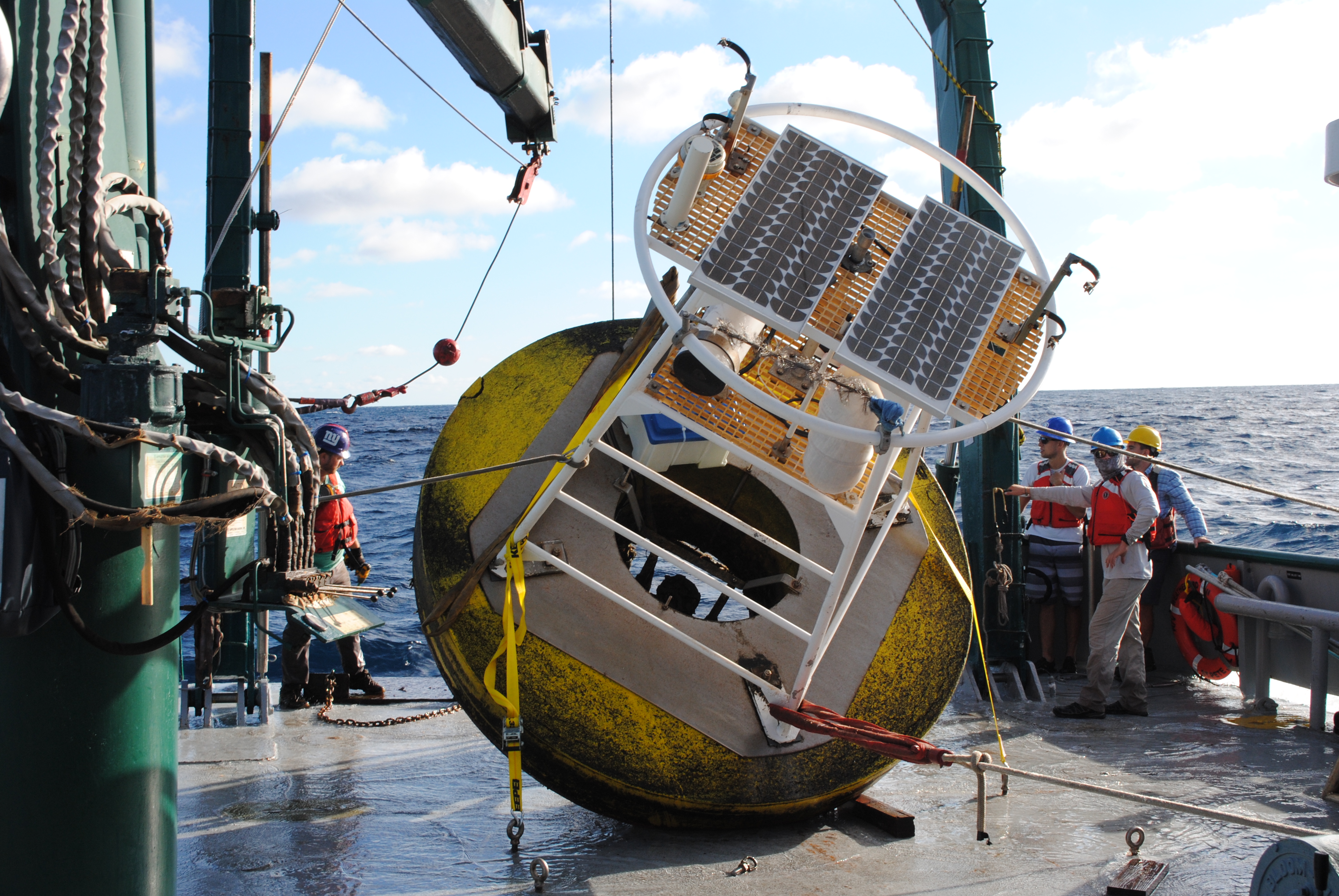 Jay Law, left, and crew with a weather buoy on the deck of the R/V Weatherbird II.